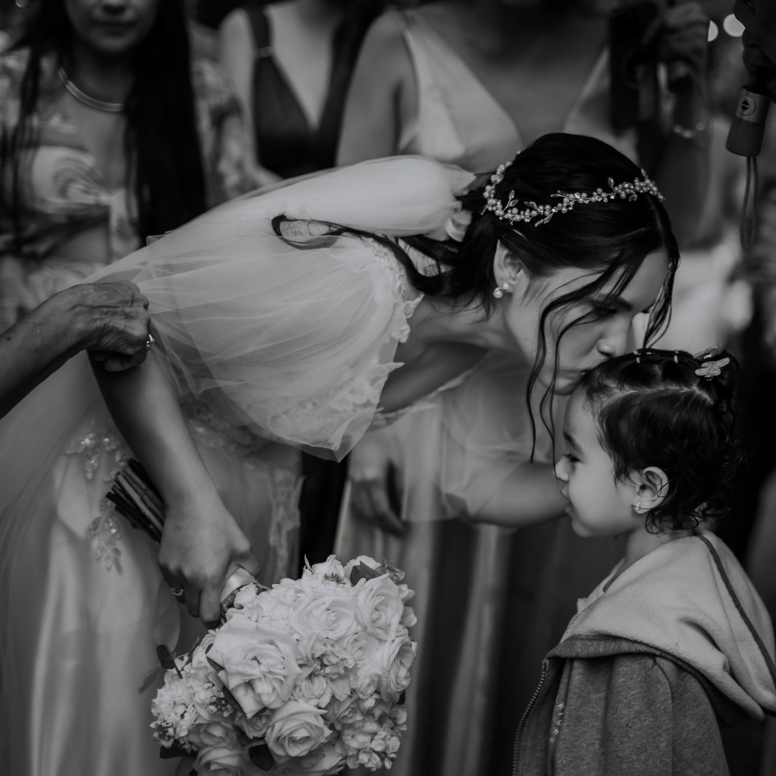 La novia besa en la frente a una niña, en blanco y negro