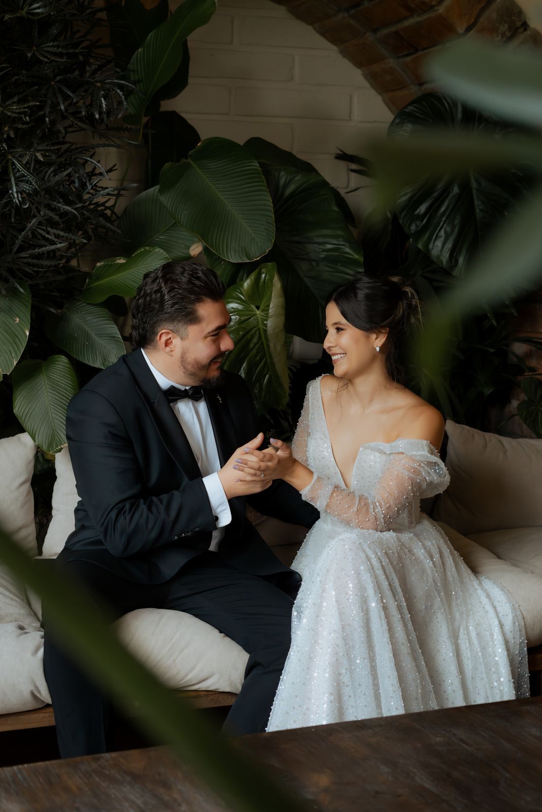 Pareja tomada de las manos entre plantas tropicales